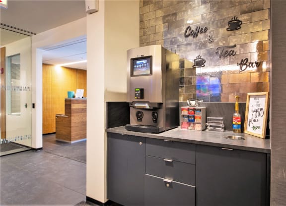 a counter with a coffee machine and a sink in front of a brick wall at One 333, Chicago, 60605