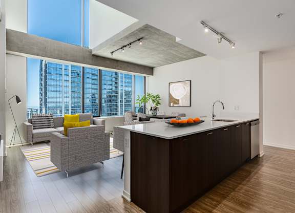 A modern kitchen with a large island and a living area with a couch and a chair.