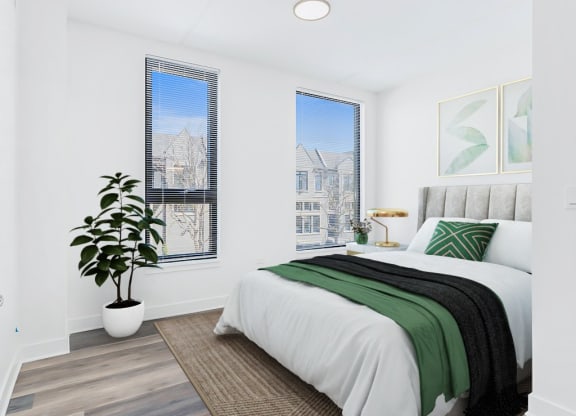 an apartment bedroom with a bed and two windows