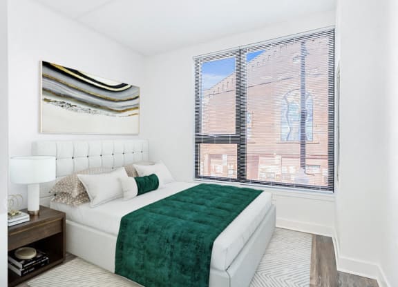 a bedroom with a large window and a bed with a green blanket