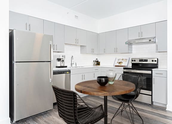 a kitchen with white cabinets and stainless steel appliances and a small table