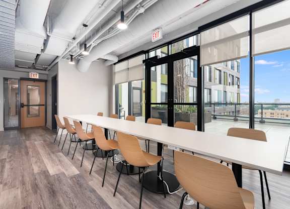 a long table and chairs in a room with glass doors