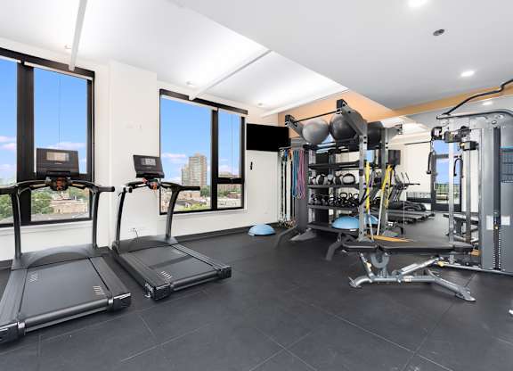 two treadmills and other exercise equipment in a gym with windows