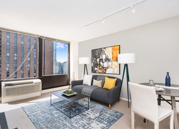 a living and dining area with a couch table and chairs and a large window with a city at Columbus Plaza, Chicago, 60601