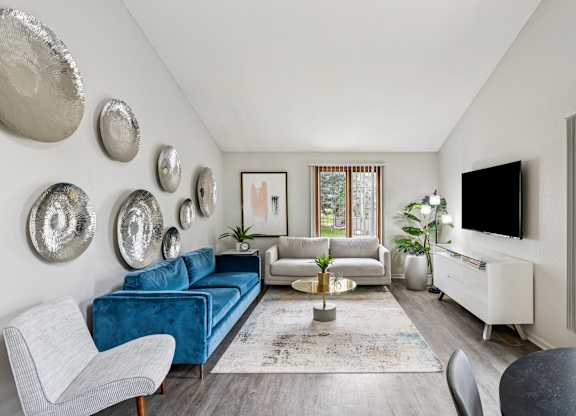 A living room with a blue couch and a television at Seasons Villas Apartments, Woodbury, MN