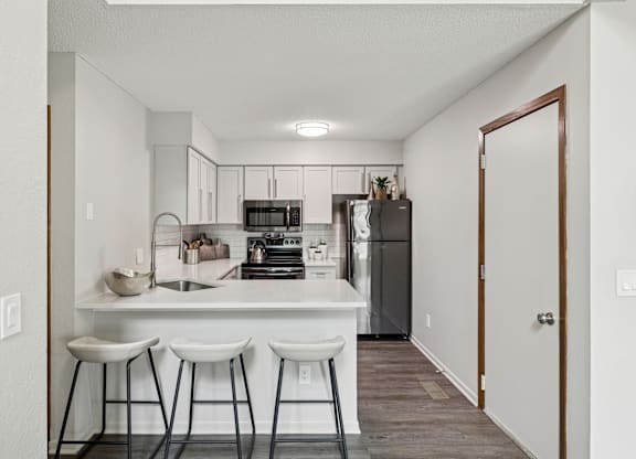 A kitchen with white countertops and bar stools at Seasons Villas Apartments, Minnesota, 55125