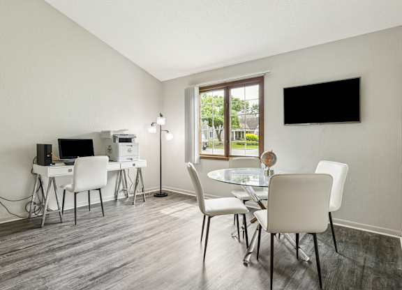 A modern dining room with a glass table and white chairs at Seasons Villas Apartments, Woodbury