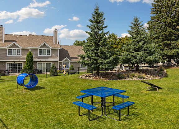 A blue picnic table is in the middle of a grassy area at Seasons Villas Apartments, Woodbury 55125