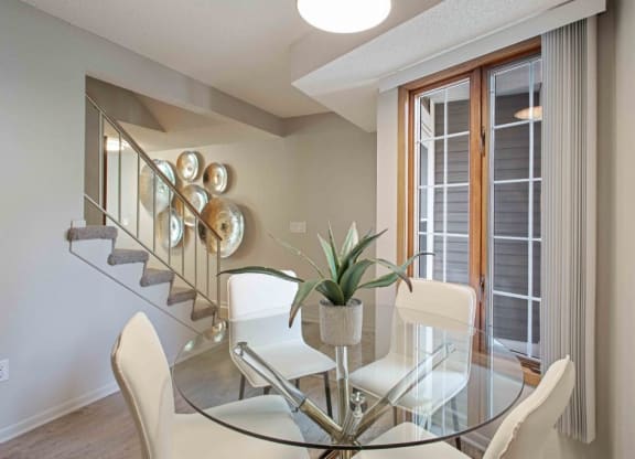 a dining room with a glass table and chairs at Seasons Villas, Woodbury Minnesota