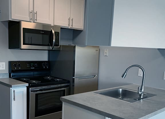 Compact kitchen with gray countertops and peninsula at Cedarvale Highlands Apartments, Eagan, 55122