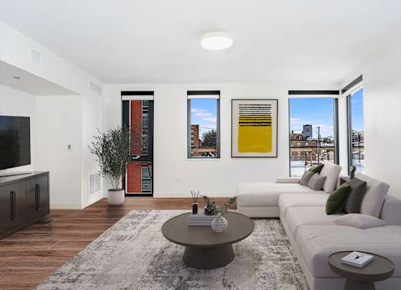 A modern living room with a white sofa, a coffee table, and a TV.