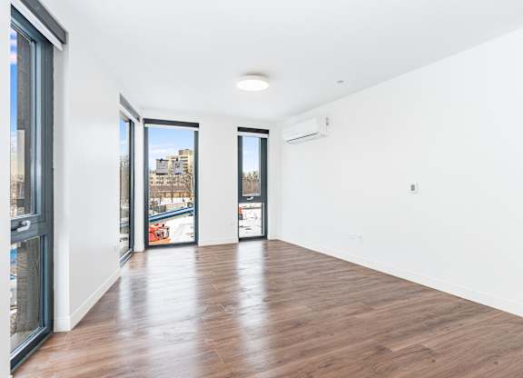 A spacious room with wooden floors and white walls.