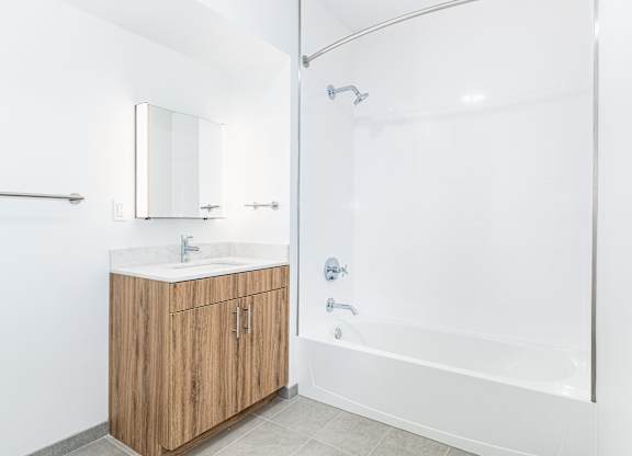 A white bathroom with a wooden vanity and a walk-in shower.