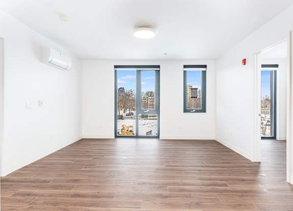 A spacious room with wooden floors and large windows.