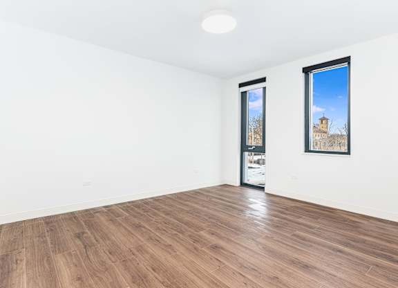 A room with a wooden floor and two windows.