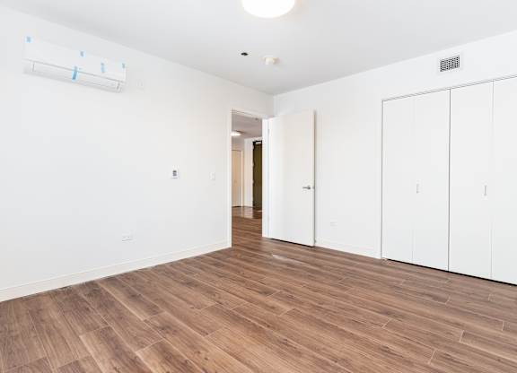 A room with wooden flooring and white walls.