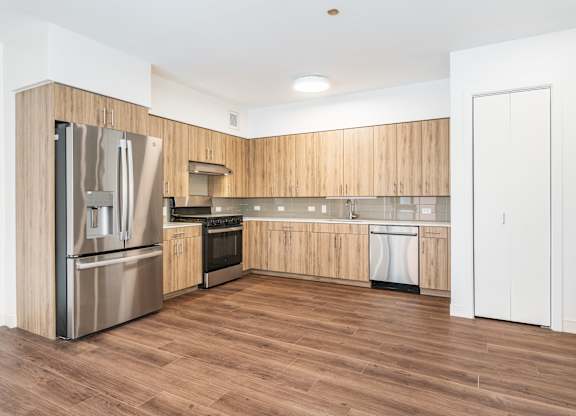 A kitchen with wooden cabinets and a stainless steel refrigerator.