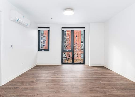 A room with a brown floor and a white wall with a window.
