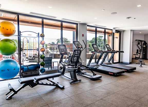 Fitness center with cardio equipment and outdoor terrace at Thrive Exchange Apartments, Chicago, IL 60617