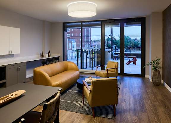 Living room with curved sofa and balcony access at Thrive Exchange Apartments, Chicago, IL