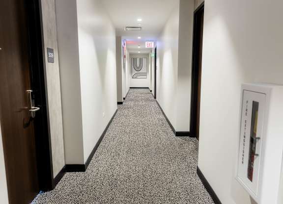 Hallway with carpeted flooring and fire extinguisher at Thrive Exchange Apartments, Chicago, 60617