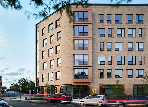 Modern brick building exterior with ground floor retail at Thrive Exchange Apartments, Chicago, 60617