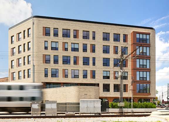 Modern apartment building exterior with train passing by at Thrive Exchange Apartments, Illinois