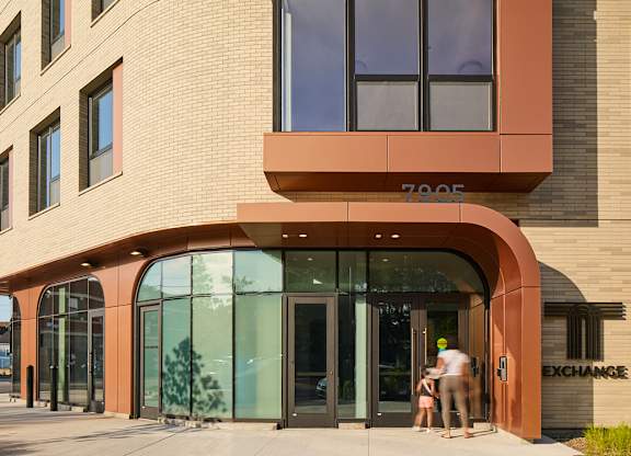 Building entrance with copper canopy and glazed doors at Thrive Exchange Apartments, Illinois, 60617