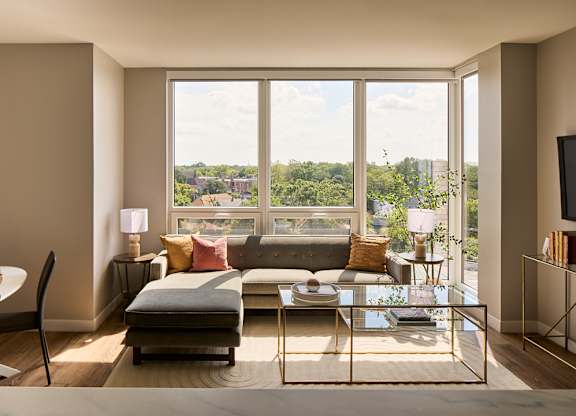 Living room with floor to ceiling windows and treetop views at Thrive Exchange Apartments, Chicago, IL