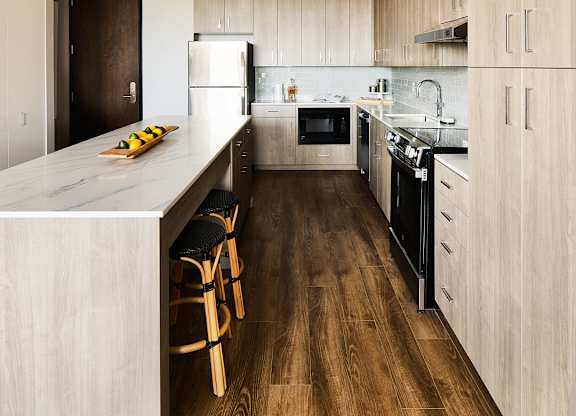 Galley kitchen with marble island and bar seating at Thrive Exchange Apartments, Chicago, 60617