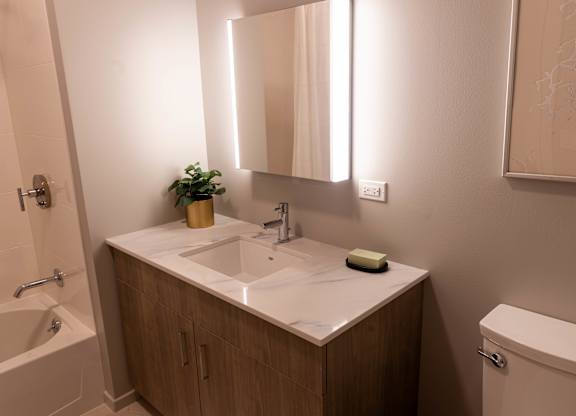 Bathroom with wood vanity and backlit mirror at Thrive Exchange Apartments, Chicago, Illinois