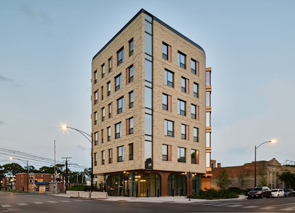 Six story brick building at dusk with arched storefronts at Thrive Exchange Apartments, Illinois
