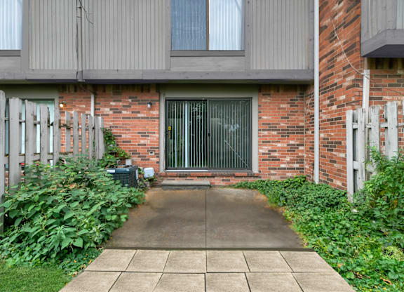 A brick building with a grey door and a concrete walkway leading to it at The Village of Hyde Park, Detroit