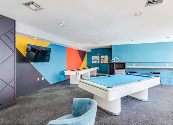 A pool table in a room with a blue chair.