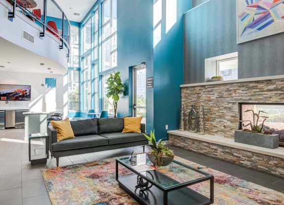 A living room with a grey couch and a glass coffee table.