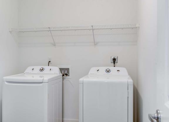 Two white washing machines in a small laundry room.