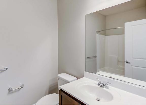 A white bathroom with a toilet, sink, and shower.