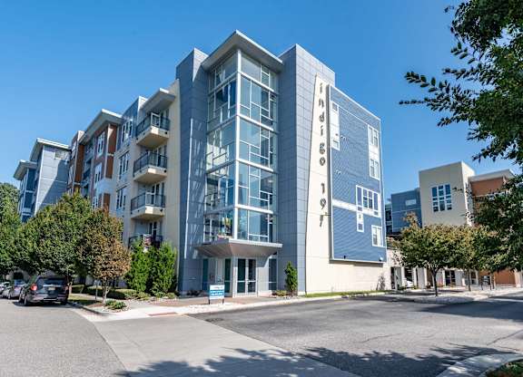 A modern multi-story building with a parking lot in front.