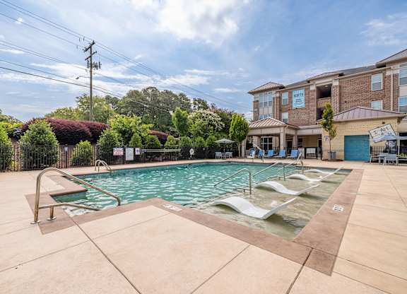 A large outdoor swimming pool with lounge chairs and a building in the background at 1701 North Apartment Homes Apartments, Chapel Hill, North Carolina