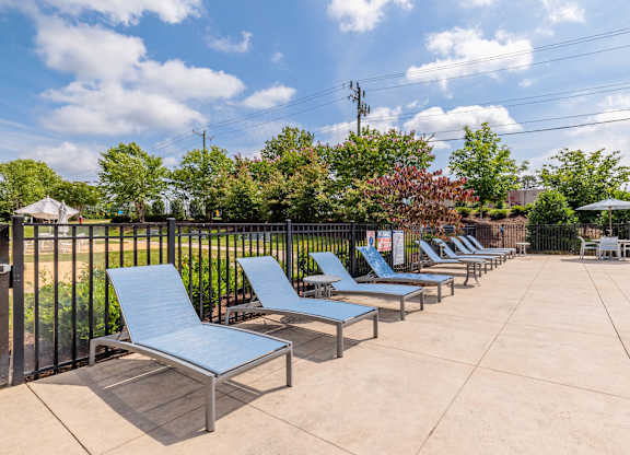 A row of blue lounge chairs are set up on a concrete patio at 1701 North Apartment Homes Apartments, Chapel Hill, NC, 27514