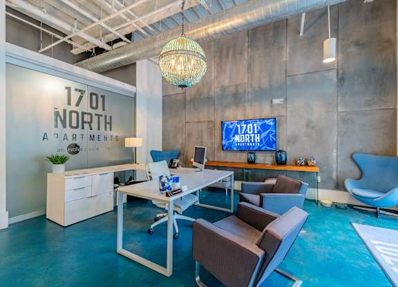A modern office space with a blue carpet and a white desk with chairs at 1701 North Apartment Homes Apartments, Chapel Hill, NC, 27514