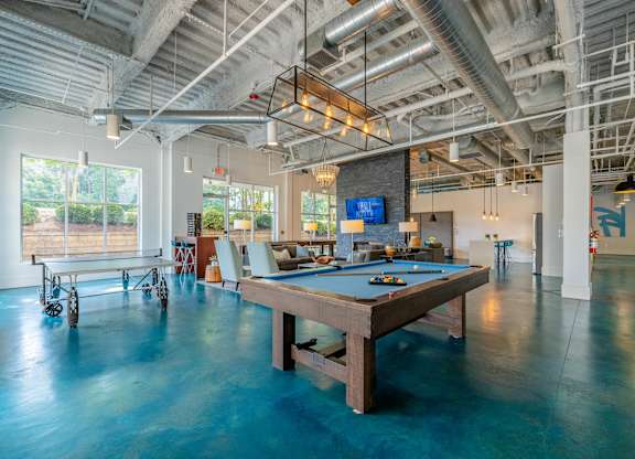 A pool table in a room with a high ceiling and exposed pipes at 1701 North Apartment Homes Apartments, North Carolina