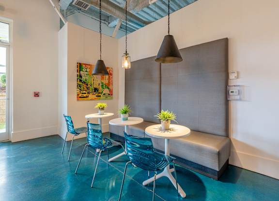 A room with a grey couch, blue chairs and a table with flowers on it at 1701 North Apartment Homes Apartments, Chapel Hill, North Carolina