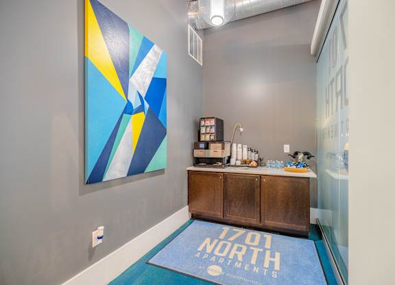 A blue and yellow abstract painting hangs on a wall above a wooden cabinet at 1701 North Apartment Homes Apartments, North Carolina, 27514