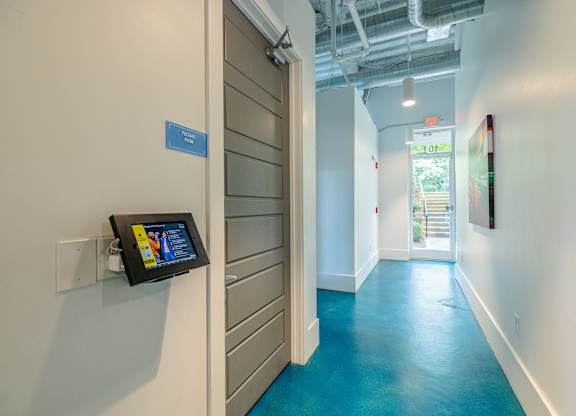 A hallway with a blue floor and a white wall with a tablet on it at 1701 North Apartment Homes Apartments, Chapel Hill, NC