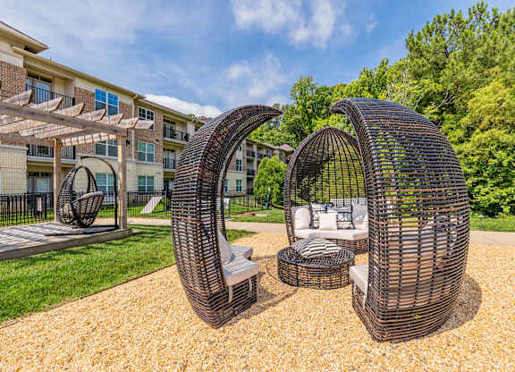 A modern outdoor seating area with two large woven structures and a small table at 1701 North Apartment Homes Apartments, Chapel Hill, North Carolina