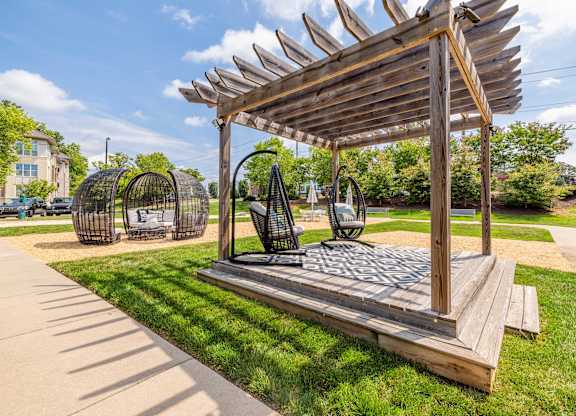 A wooden structure with a canopy and a bench underneath it at 1701 North Apartment Homes Apartments, Chapel Hill, 27514