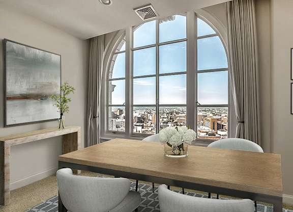 A dining room with a table, chairs, and a view of the city through large windows.