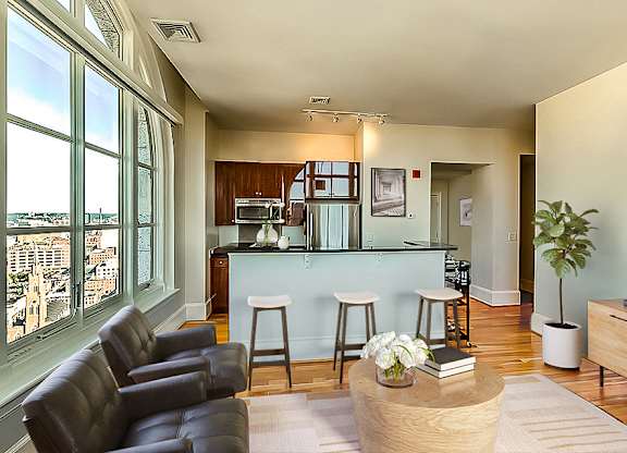 A living room with a bar area and a view of the city.