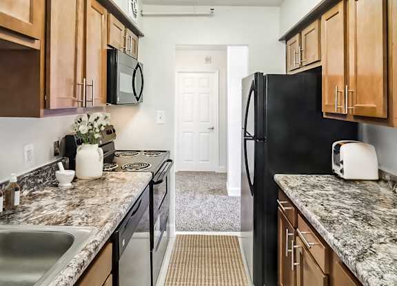A kitchen with a black refrigerator and wooden cabinets.